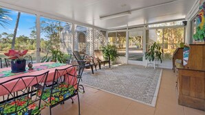 A sunlit patio with a table, chairs, and a view of the surrounding landscape.
