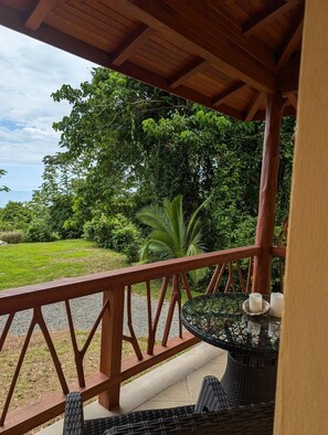 A wooden deck with a table and chairs, surrounded by lush greenery and a view of the landscape. - Casa Arabella- Ocean, Jungle views, Wildlife, Pool, Beach Club, AC.... 5 Star! (Uvita)