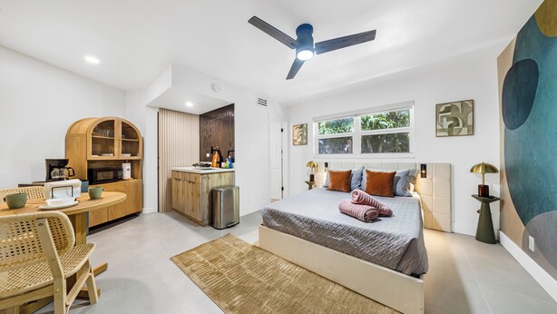 Un dormitorio moderno con cama, mesita de noche y ventilador de techo.