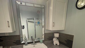 A bathroom with a white sink, mirror, and cabinets. - Private Room Downtown with Kitchenette (Edmonton)