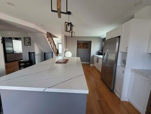 Eine moderne Küche mit einer großen Kochinsel, Edelstahlgeräten und einer Holztreppe.