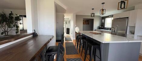 A modern kitchen with a central island, bar seating, and a dining area with a wooden table and chairs.