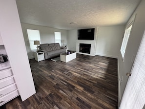A living room with a sofa, coffee table, fireplace, and a TV mounted on the wall.