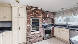 A kitchen with white cabinets, a brick accent wall, a built-in oven, and a window. - World Cup Boston Private 6-Acre Estate Sleeps 16 Less than 18 Min From Gillette (Taunton)