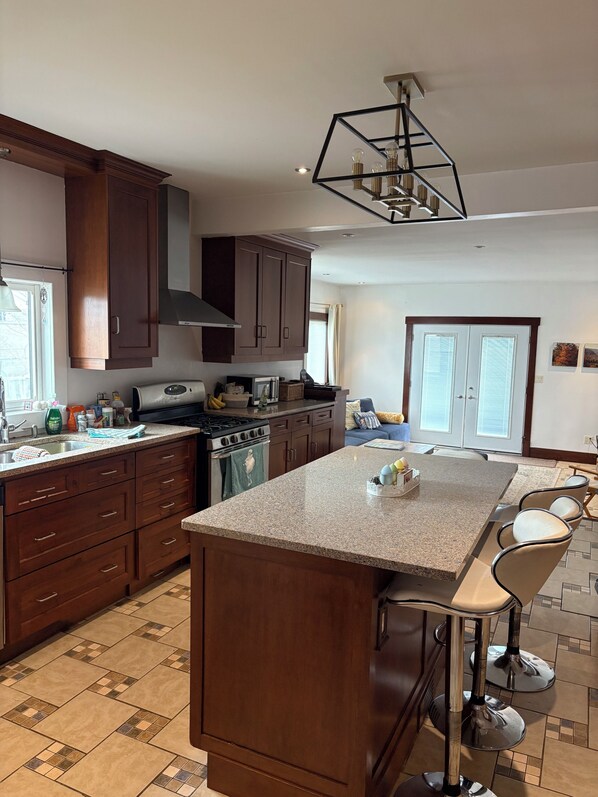 A modern kitchen with dark wood cabinets, a granite countertop island, and a built-in stove.