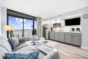 A modern living room with a sofa, coffee table, and a view of the balcony. - Experience Oceanfront Balcony Sunrises (North Myrtle Beach)