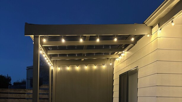 Eine Terrasse im Freien mit Pergola, Sitzbereich und Lichterketten.