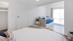 Ein Schlafzimmer mit einem Bett, einem Deckenventilator, einem Fenster und einer Tür.