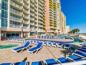 Ein Hotel mit Poolbereich, mehreren Balkonen und blauem Himmel.