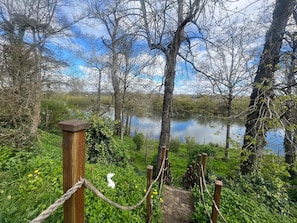 A wooden bridge leading to a lake surrounded by trees and greenery. - Beautiful riverside home on the Dordogne River (Eynesse)