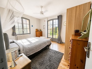 A bedroom with a bed, a dresser, a mirror, and a window. - Beautiful riverside home on the Dordogne River (Eynesse)