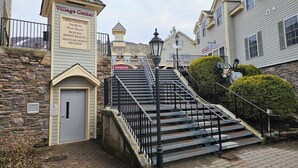 A Village Center with a stone wall entrance, a ticket booth, a clock tower, and a staircase leading to upper levels. - Year-round fun!  Condo at Jiminy Peak Resort.  Treat yourself! (Hancock)