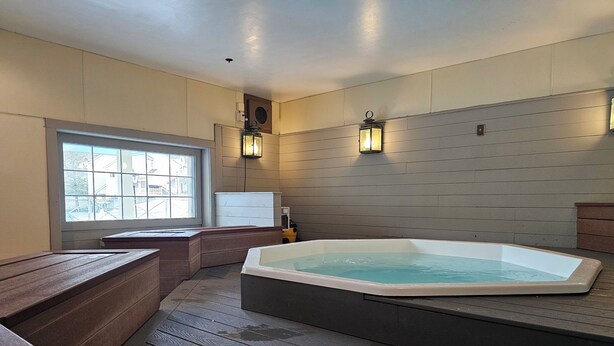 A spa room with a hot tub, wooden benches, a window, and wall-mounted lights. - Year-round fun!  Condo at Jiminy Peak Resort.  Treat yourself! (Hancock)