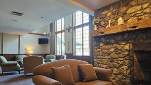 A cozy room with a stone fireplace, comfortable seating, large windows, and a flat-screen TV. - Year-round fun!  Condo at Jiminy Peak Resort.  Treat yourself! (Hancock)