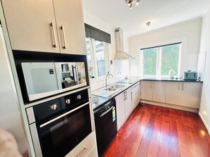 A modern kitchen with stainless steel appliances, a dishwasher, and a window providing natural light. - Spacious 5 Bedrooms Fully Fenced house in Auckland (Mount Roskill)