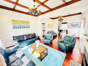 A spacious living room with a modern chandelier, leather sofas, and a wooden coffee table. - Spacious 5 Bedrooms Fully Fenced house in Auckland (Mount Roskill)