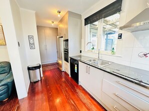 Una cocina moderna con armarios blancos, un lavamanos de acero inoxidable y un horno empotrado.