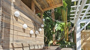 Una estructura de madera al aire libre con un barril, escalones y luces colgantes.