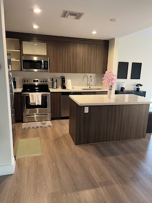 A modern kitchen with dark wood cabinets, stainless steel appliances, and a central island. - BEAUTIFUL DOWNTOWN HOLLYWOOD BEACH YOUNG CIRCL 2B 2B Apt (Hollywood)
