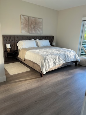 A bedroom with a large bed, a nightstand, a bedside table, a window, and a view of greenery outside. - BEAUTIFUL DOWNTOWN HOLLYWOOD BEACH YOUNG CIRCL 2B 2B Apt (Hollywood)
