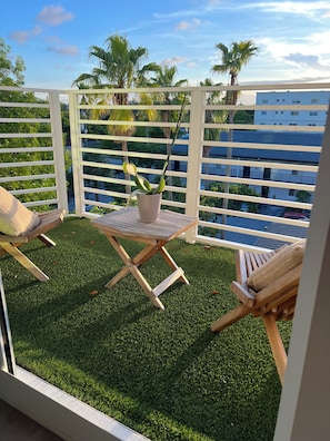A balcony with artificial grass, a potted plant, and two wooden chairs. - BEAUTIFUL DOWNTOWN HOLLYWOOD BEACH YOUNG CIRCL 2B 2B Apt (Hollywood)