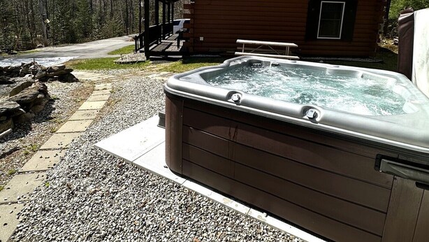 A wooden cabin with a hot tub, a covered deck, and a picnic table. - Cozy, peaceful cabin retreat with hot tub (Weld)