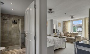 Ein Schlafzimmer mit Bett, einem Fenster mit Vorhängen, einer Couch und einem kleinen Tisch.