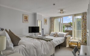 Ein Schlafzimmer mit einem Bett, einem Fernseher, einer Heizung und einem Fenster mit Vorhängen.