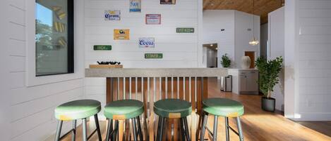 A bar area with stools, a wooden ceiling, and a wall with various brand signs.
