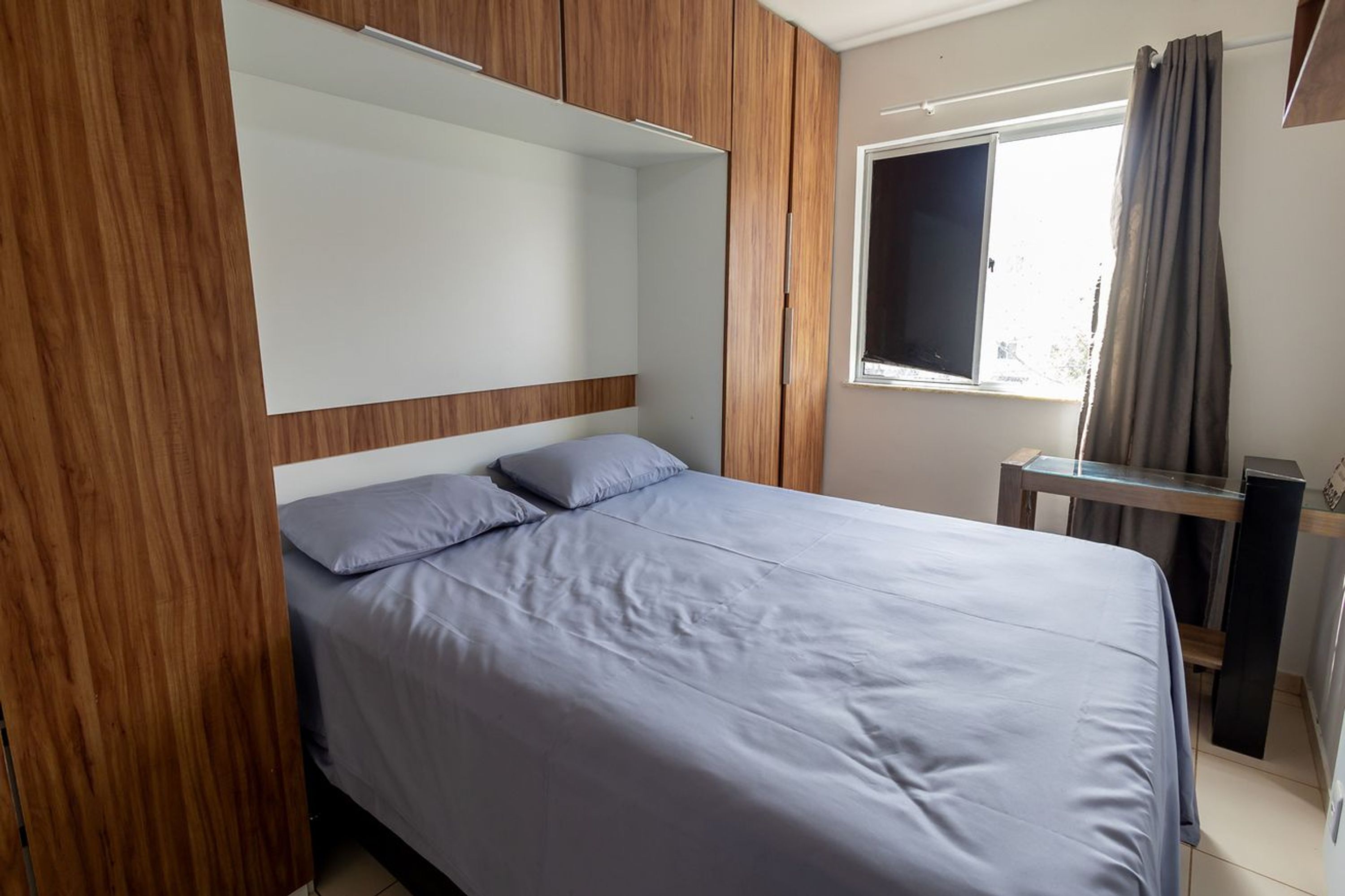 A bedroom with a bed, a window, and a desk.