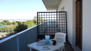 Ein Balkon mit Tisch für zwei Personen, einem Stuhl und Blick auf den Strand.
