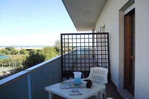 Ein Balkon mit Tisch für zwei Personen, einem Stuhl und Blick auf den Strand.