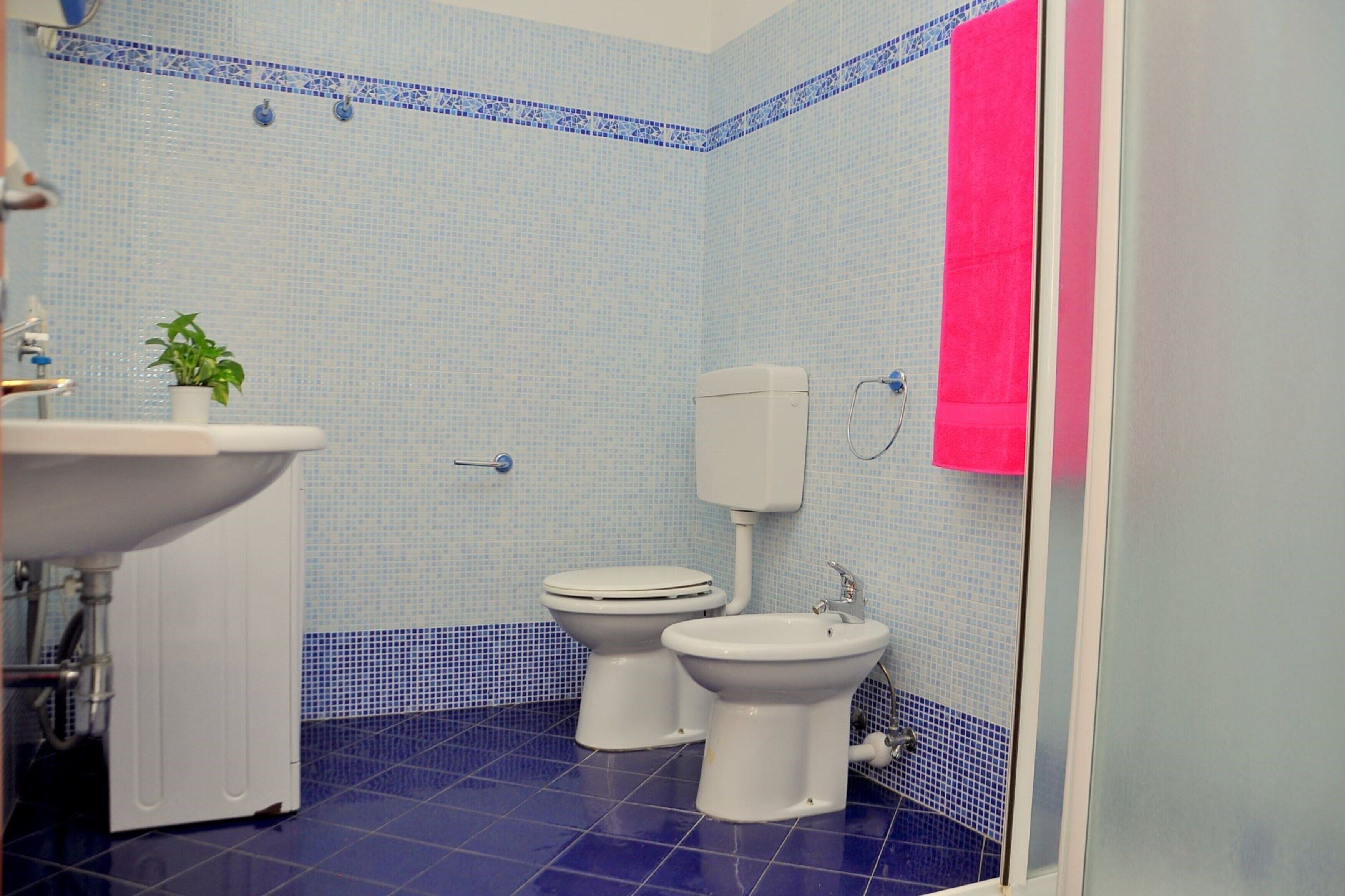 A bathroom with a sink, two toilets, a bidet, and a toilet paper holder.