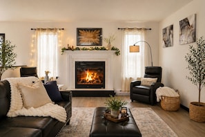 Ein Wohnzimmer mit Kamin, Ledersofas, einem Couchtisch und Zierpflanzen.