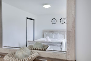 Ein Schlafzimmer mit einem Bett, einem Spiegel und einer dekorativen Schale auf einer Holztischplatte.