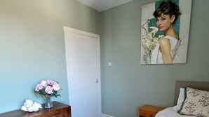 Un dormitorio con cama, cómoda, mesita de noche y un cuadro en la pared.