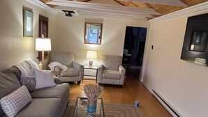 Ein Wohnzimmer mit einer Couch, zwei Sesseln, einem Couchtisch und einer Lampe.