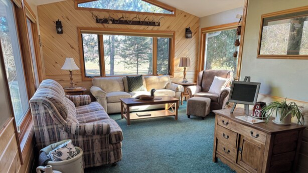 Ein gemütliches Wohnzimmer mit Kamin, großen Fenstern und rustikalem Holzinterieur.