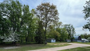 Ein Campingplatz mit einem gepflasterten Weg, Picknicktischen und einem großen Scheune.