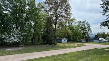Un terrain de camping doté d’un chemin pavé, de tables de pique-nique et d’une grande grange.