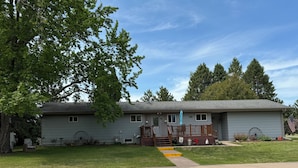 Ein Bungalow mit Veranda, kleiner Terrasse und Vorgarten.