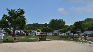 Un parc au bord de la plage, équipé d’une aire de jeux avec des balançoires, d’un kiosque et d’une rangée de chaises de plage.