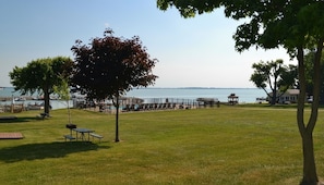 A grassy park area with picnic tables, a gazebo, and a view of the water.