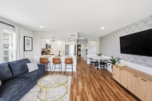 A modern living room with a sofa, a coffee table, and a TV. - Surf City Luxury Condo · Ocean Views · Pool (Surf City)