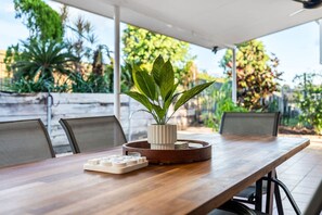 Ein Holztisch mit einem Blumentopf, einer Tablett mit Spielkarten und einem weißen Spielbrett.