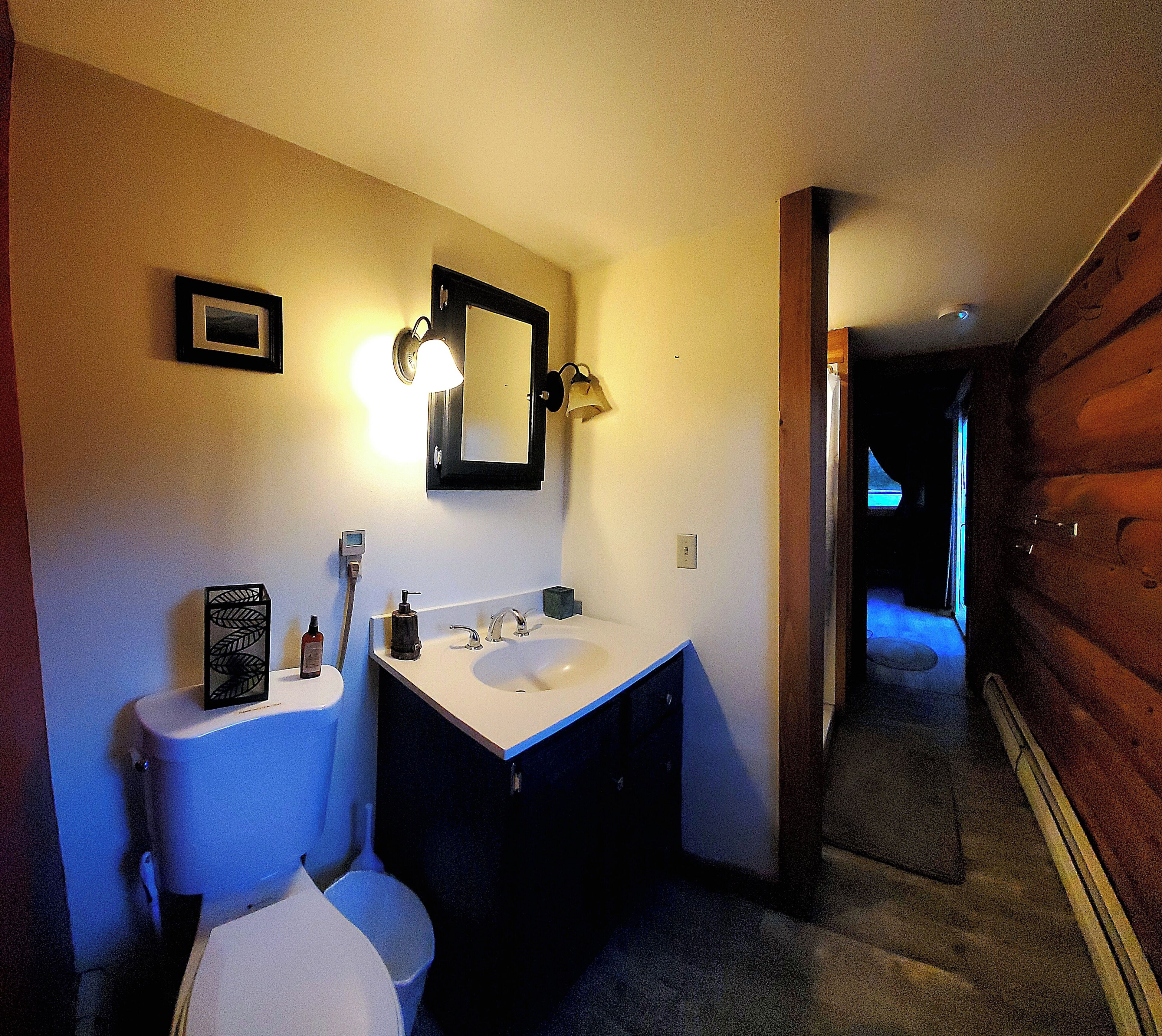 Ein Badezimmer mit Toilette, Waschbecken, Spiegel und Wandleuchten.