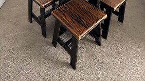 Une table carrée en bois, accompagnée de quatre bancs assortis, et deux verres à vin posés sur la table.