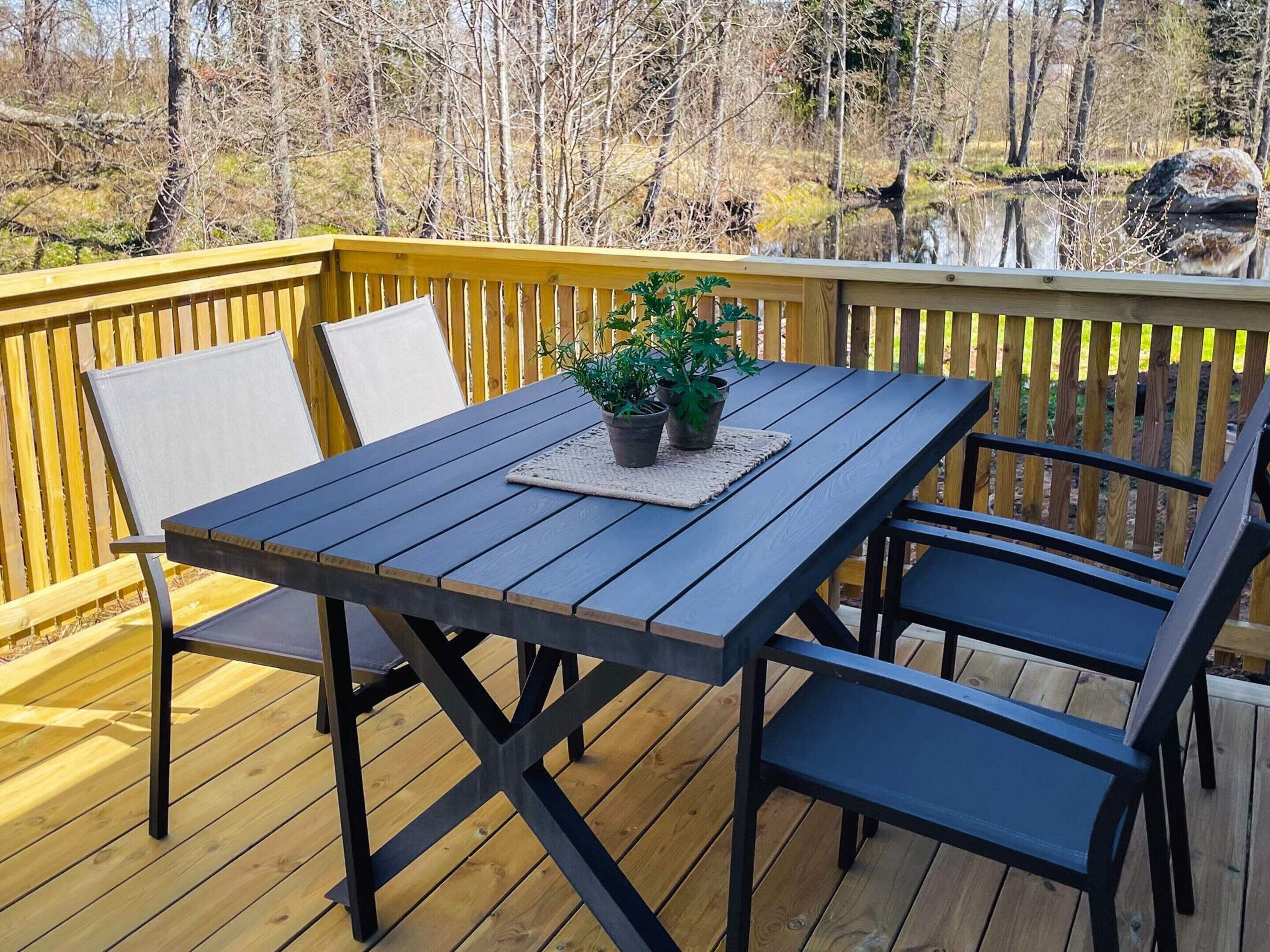 A wooden deck with a table and chairs, surrounded by a yellow railing.