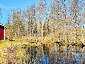 Eine friedliche Flusslandschaft mit einem roten Gebäude, umgeben von Bäumen und ruhigem Wasser.
