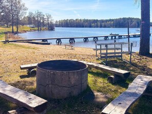 Ein Campingplatz am Seeufer mit Feuerstelle, Picknicktischen und einer Anlegestelle, die ins Wasser ragt.